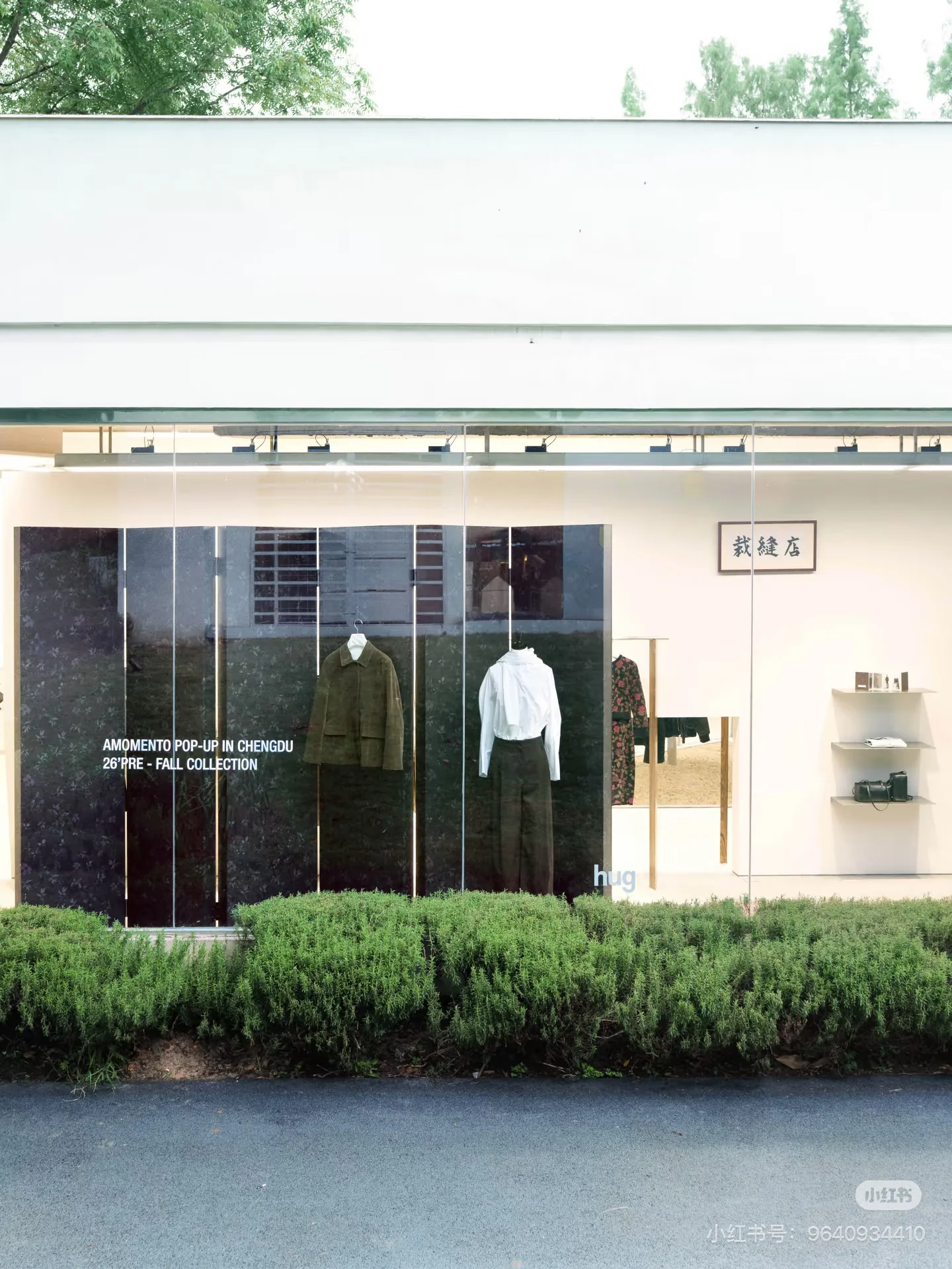 The glass-fronted hug store with clothing displays and planted greenery.