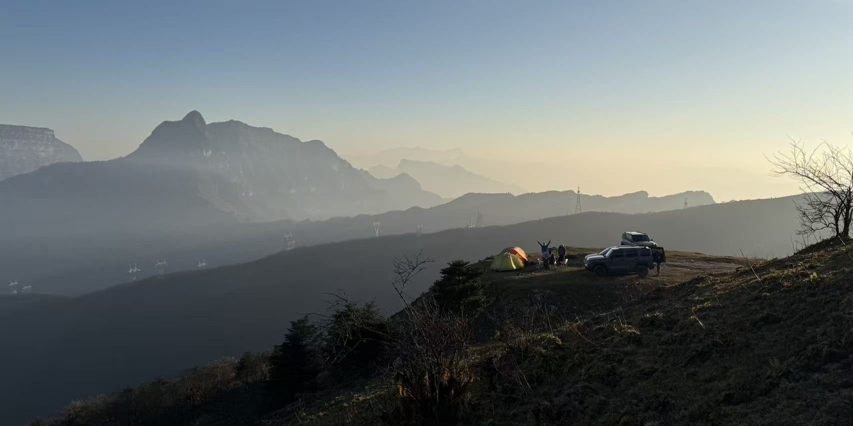 A mountain campsite with tents and vehicles in the early morning light