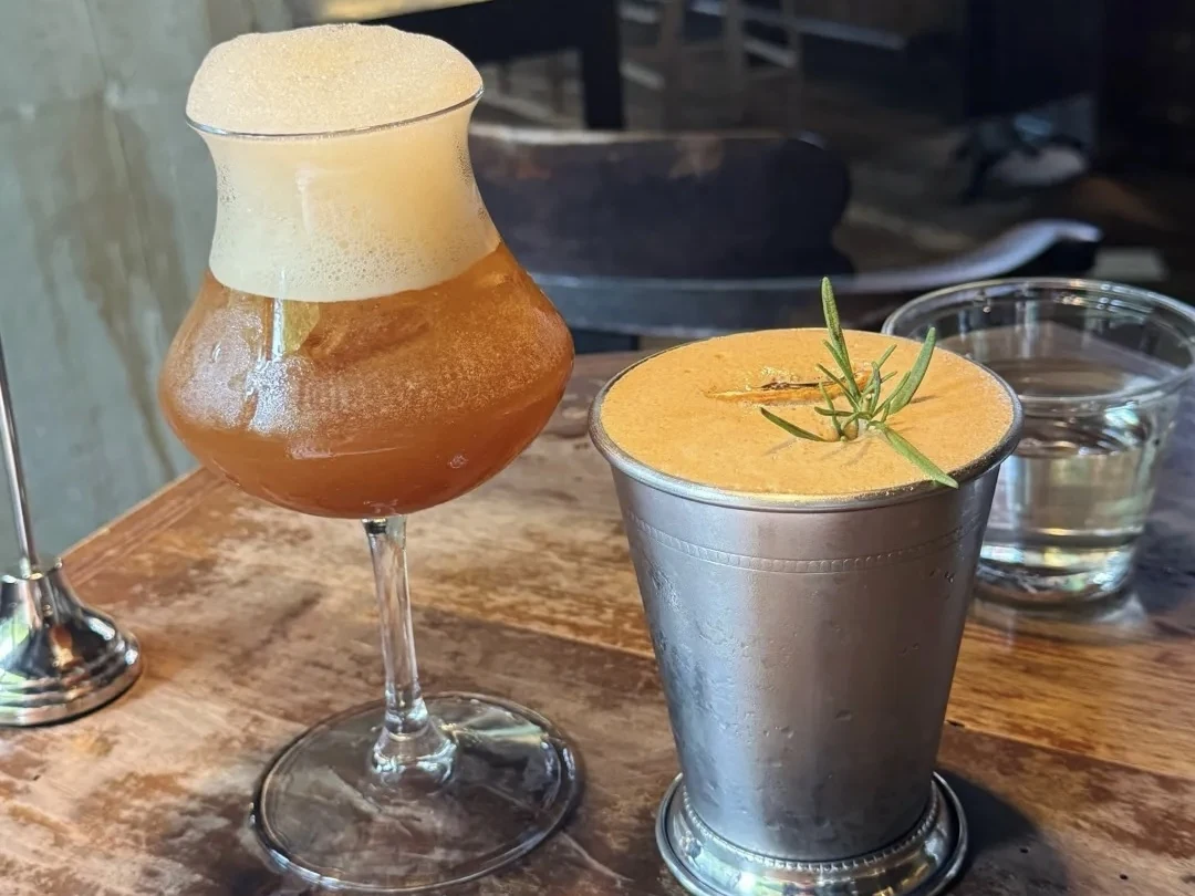 Two drinks on a wooden table at LittleTravel CPI.