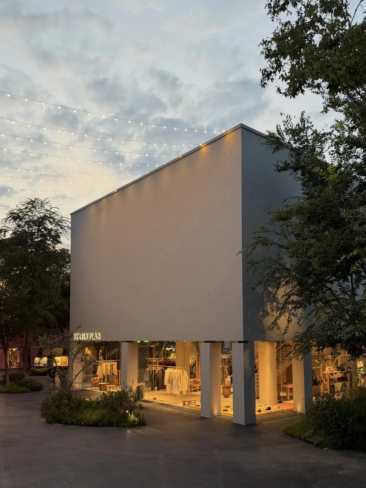 The illuminated YEARLY PLAN HOUSE exterior at dusk.