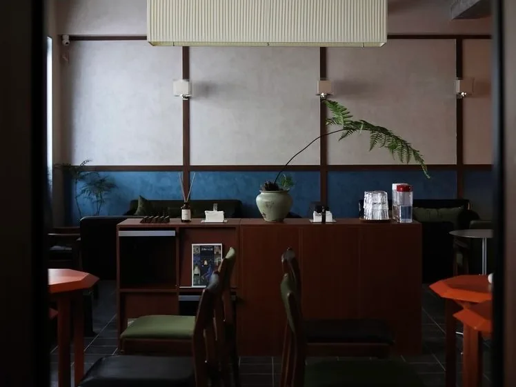 Wooden furniture, green seating and plants inside WalkingNotes