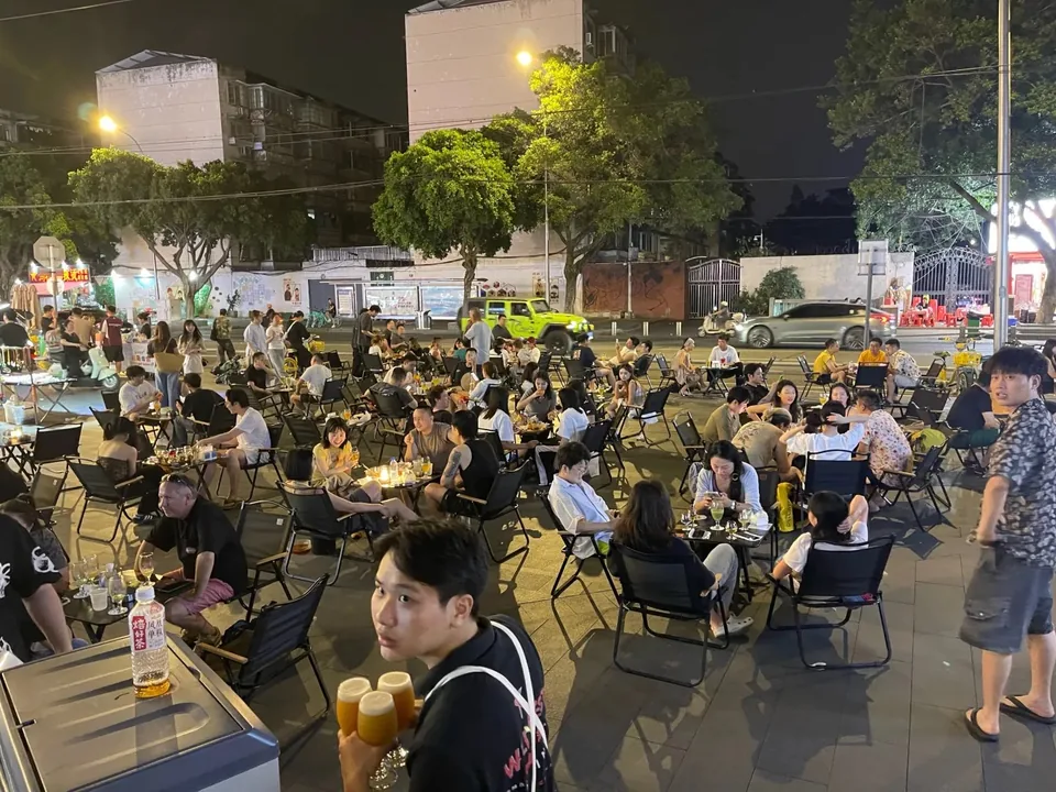 People enjoying drinks at outdoor tables at Wild West Brewing in the evening